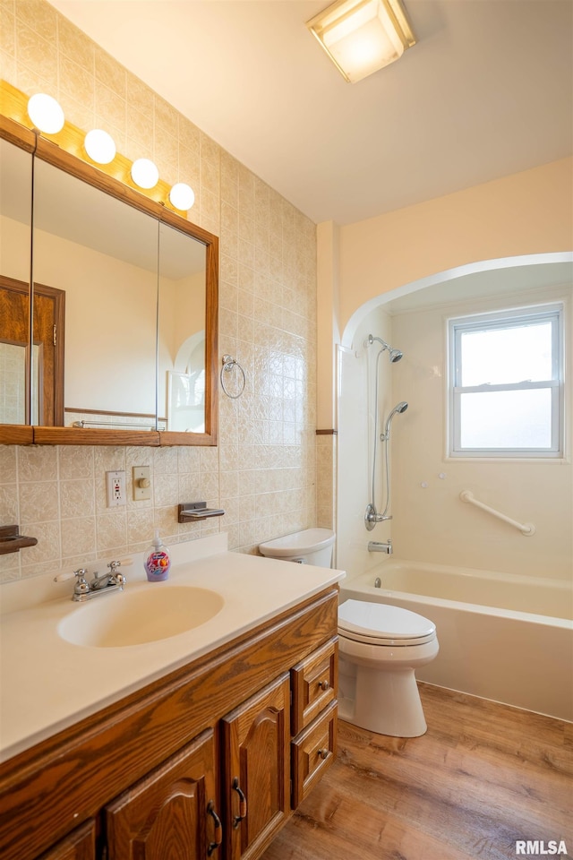 full bathroom with tile walls, hardwood / wood-style flooring, vanity, toilet, and bathing tub / shower combination