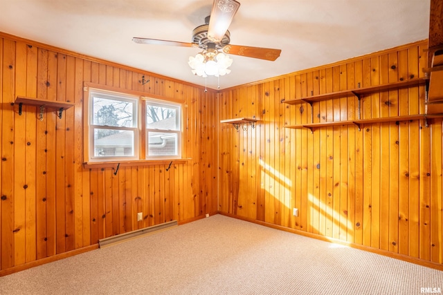 spare room with a baseboard radiator, carpet, wooden walls, and ceiling fan