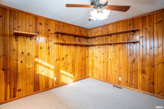 unfurnished room featuring wooden walls, ceiling fan, and carpet flooring