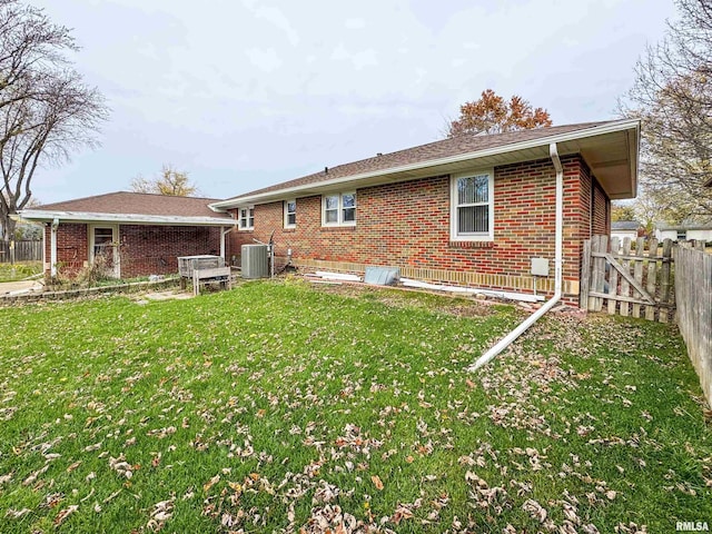 back of property featuring central AC and a yard