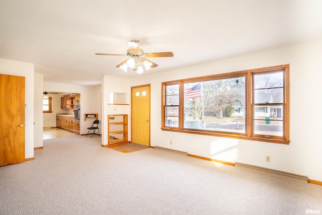 carpeted spare room with a baseboard radiator and ceiling fan