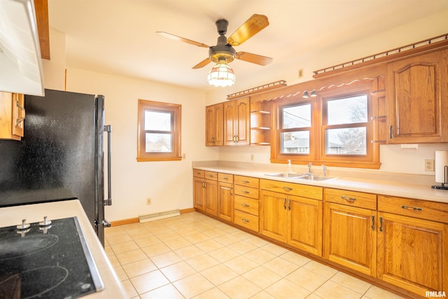 kitchen with sink, stainless steel fridge, ceiling fan, black stovetop, and light tile patterned flooring