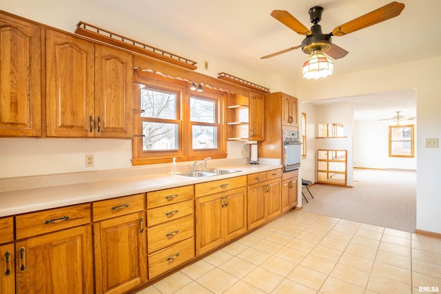 kitchen with sink, light colored carpet, oven, and ceiling fan