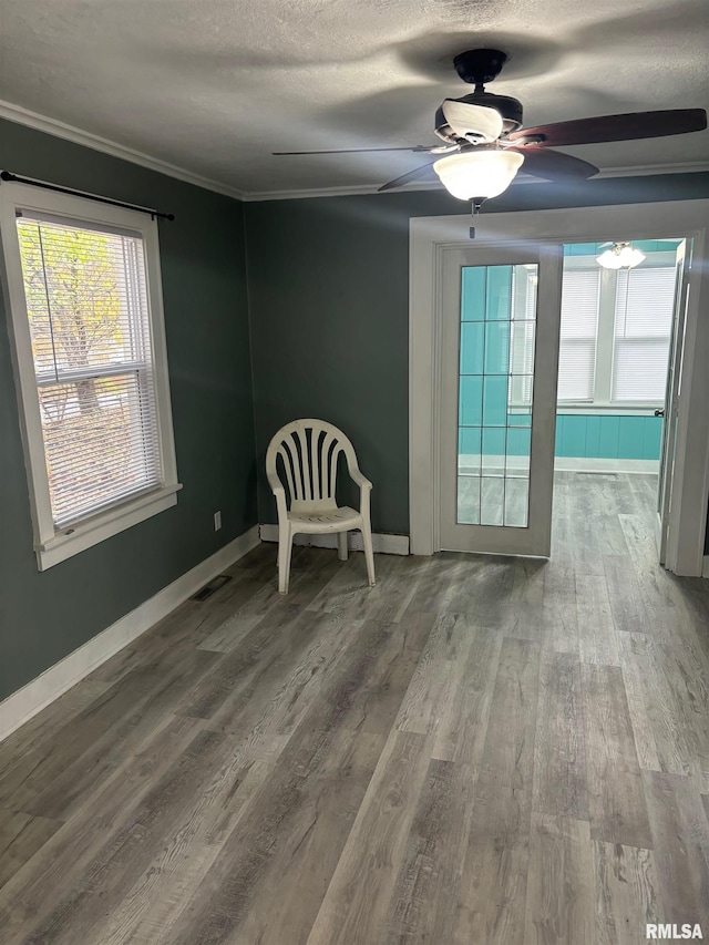 interior space with crown molding, ceiling fan, wood-type flooring, and a textured ceiling