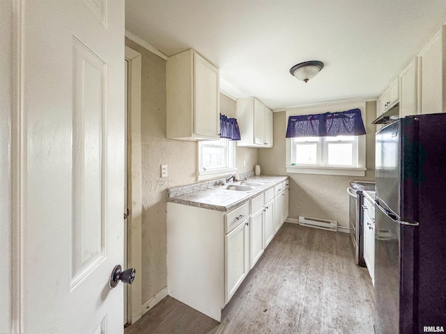 kitchen with sink, black fridge, light hardwood / wood-style floors, stainless steel electric stove, and white cabinets