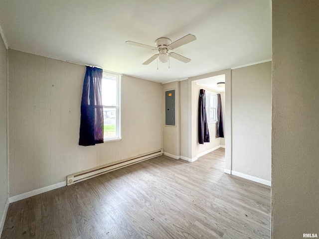 spare room featuring electric panel, ceiling fan, light hardwood / wood-style flooring, and a baseboard heating unit