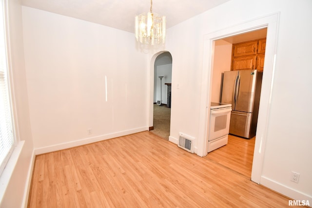 spare room with an inviting chandelier and light hardwood / wood-style flooring