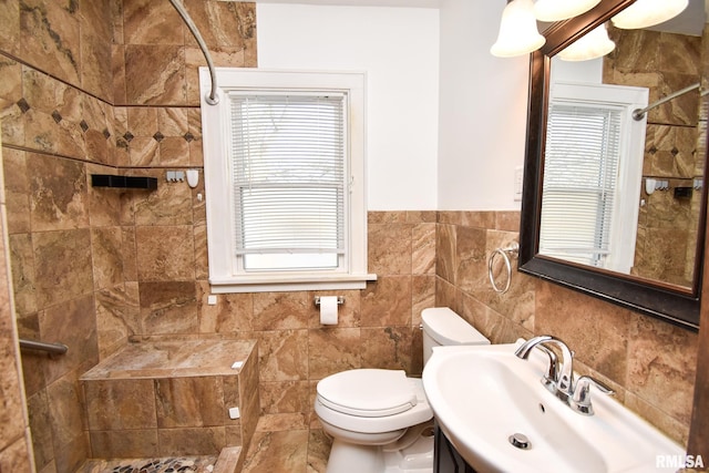 bathroom featuring a tile shower, vanity, tile walls, and toilet