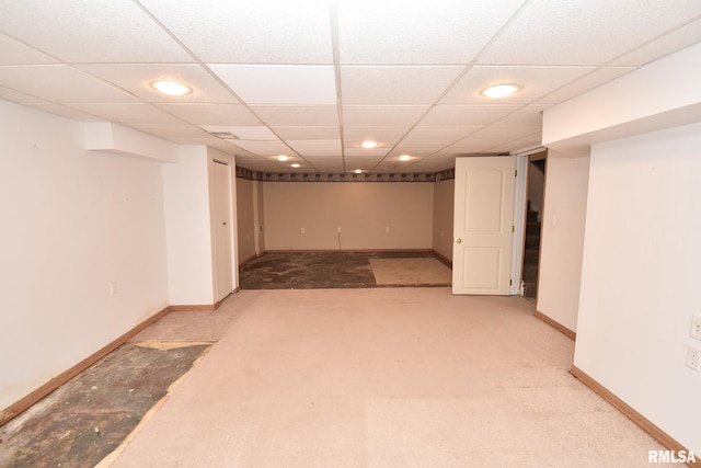 basement featuring a paneled ceiling and light colored carpet