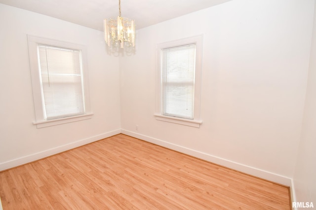 unfurnished room with hardwood / wood-style floors and an inviting chandelier