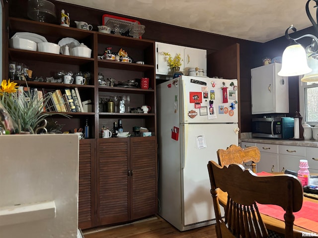 kitchen with white fridge, white cabinetry, and hardwood / wood-style flooring