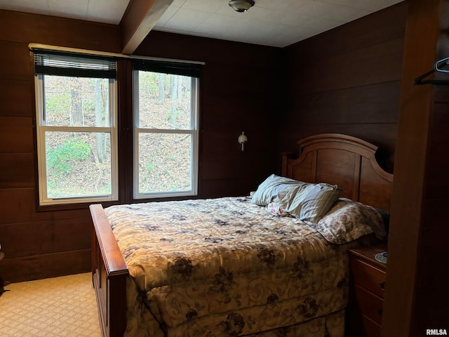 bedroom featuring multiple windows, wood walls, and light carpet