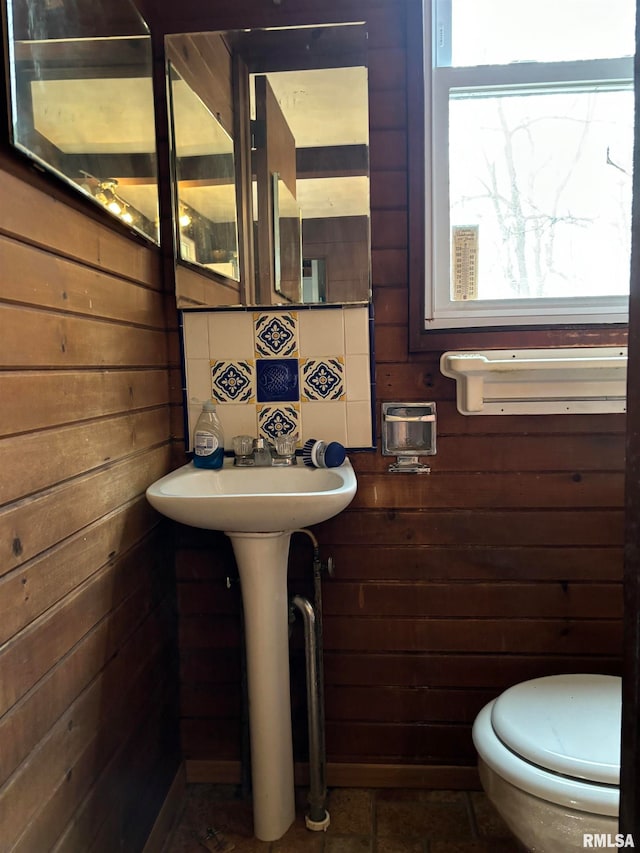 bathroom featuring toilet and wooden walls