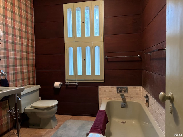 bathroom featuring wood walls, a washtub, tile patterned flooring, and toilet