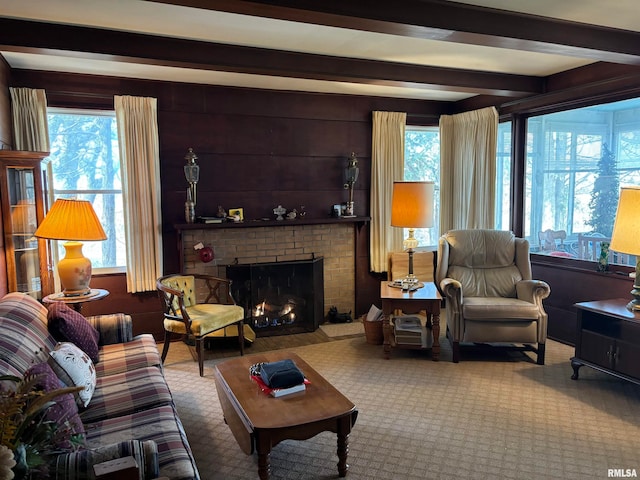 carpeted living room featuring beam ceiling, a brick fireplace, plenty of natural light, and wooden walls