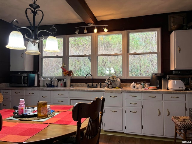 kitchen featuring white cabinets, decorative light fixtures, and sink