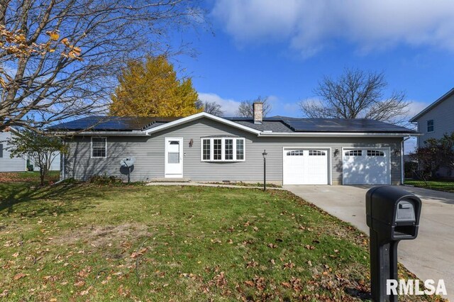 view of front of property featuring a front lawn, a garage, and solar panels