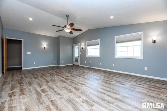 empty room with ceiling fan, lofted ceiling, and light wood-type flooring