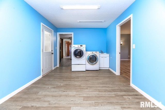 laundry area with separate washer and dryer, cabinets, and light wood-type flooring