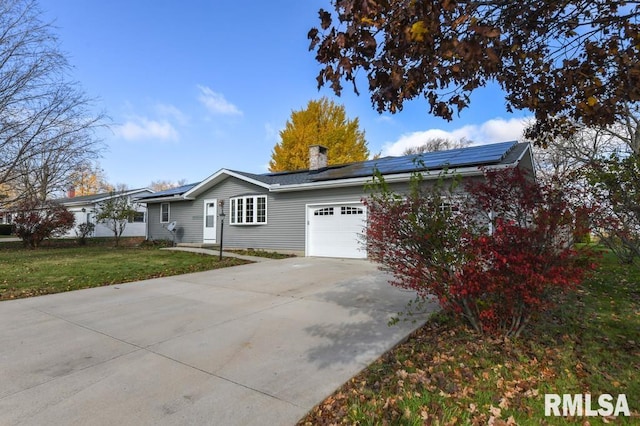 exterior space with a garage, a front lawn, and solar panels