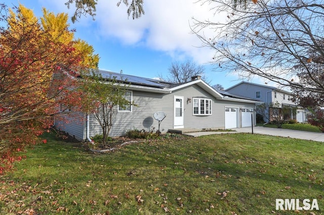 view of front of house with a garage, a front lawn, and solar panels