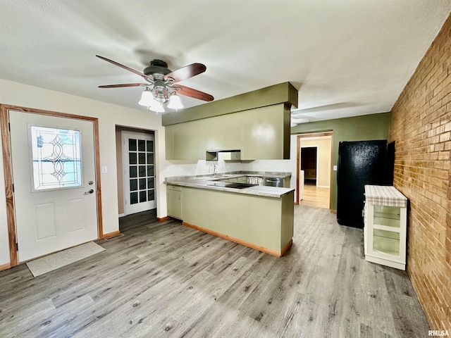 kitchen with ceiling fan, brick wall, sink, and light hardwood / wood-style floors