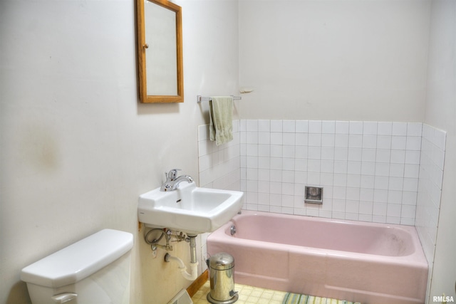 bathroom with a washtub, toilet, and sink