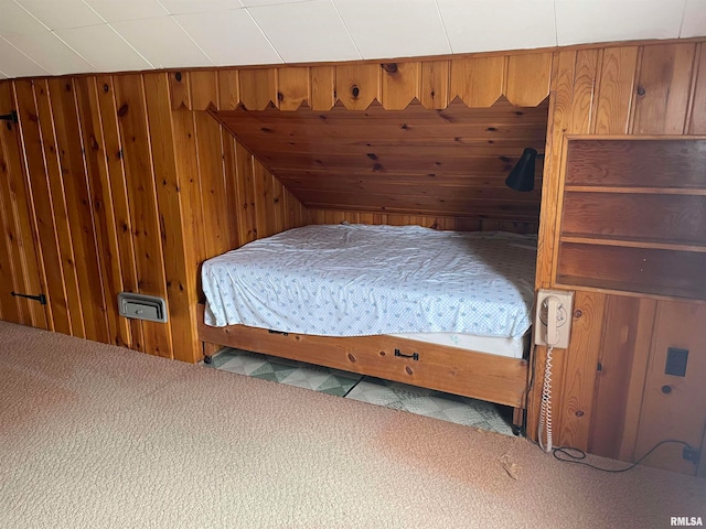 bedroom with wood walls and light carpet