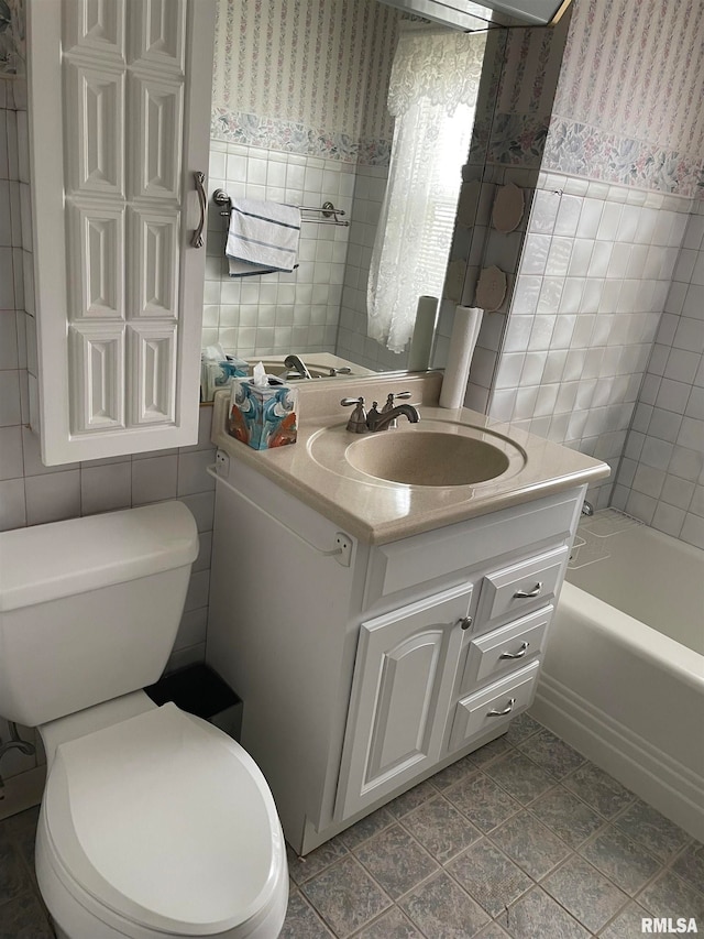 bathroom with vanity, toilet, tile walls, and a bathing tub