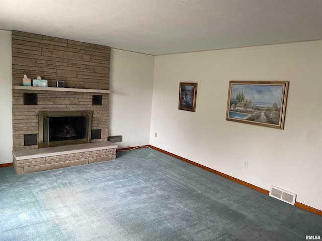 unfurnished living room with carpet flooring, a textured ceiling, and a stone fireplace