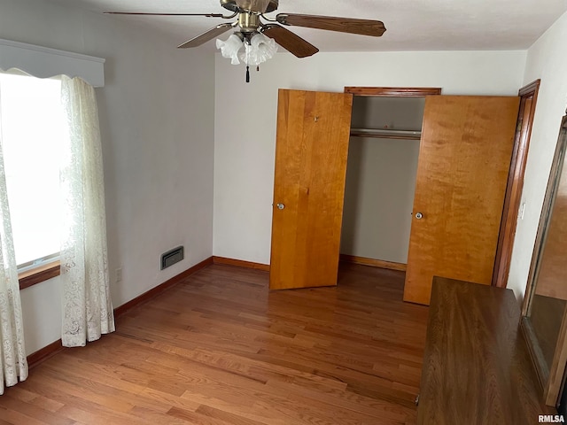 unfurnished bedroom with ceiling fan, light wood-type flooring, and a closet