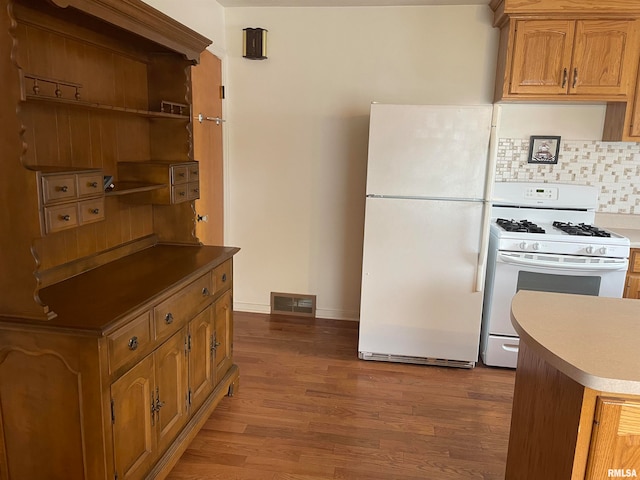 kitchen featuring backsplash, white appliances, and hardwood / wood-style flooring