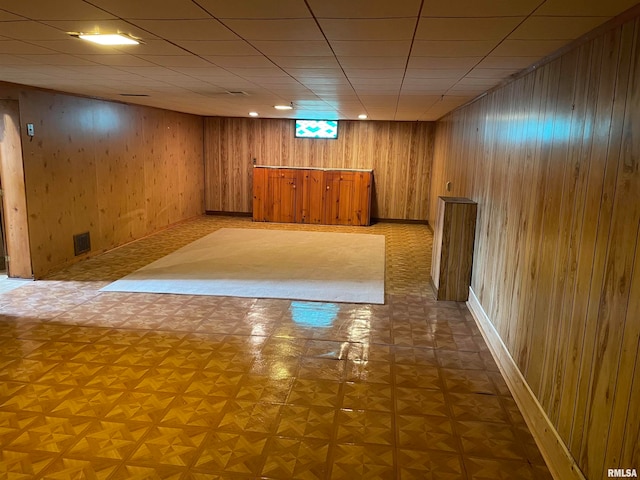 basement with wood walls, indoor bar, and parquet flooring