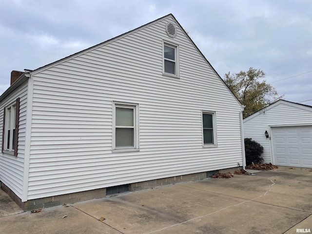 view of side of home featuring a garage and an outbuilding