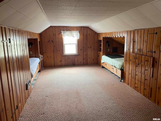 unfurnished bedroom featuring carpet, lofted ceiling, and wood walls