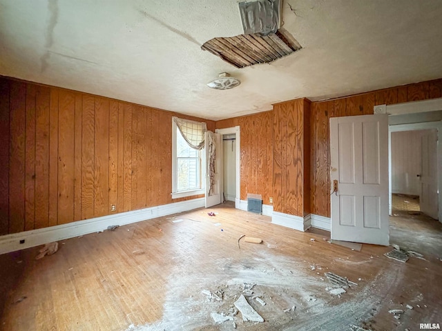 unfurnished bedroom with hardwood / wood-style flooring and wooden walls