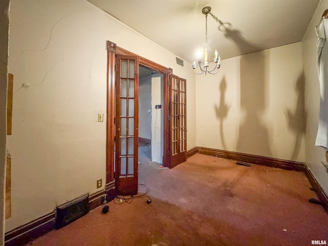 spare room with carpet flooring, french doors, and a notable chandelier