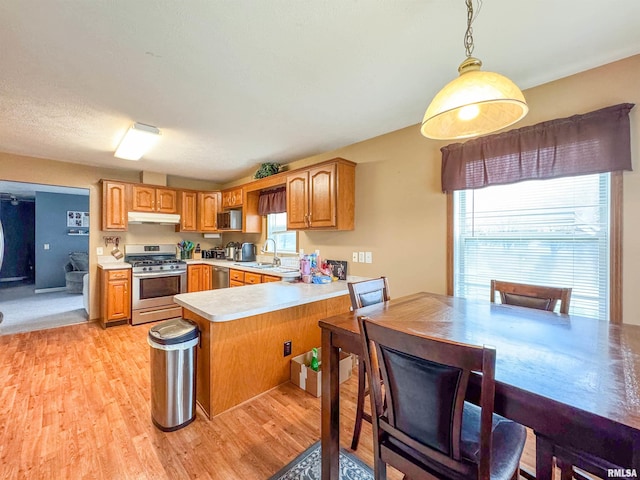 kitchen featuring sink, hanging light fixtures, light wood-type flooring, appliances with stainless steel finishes, and kitchen peninsula