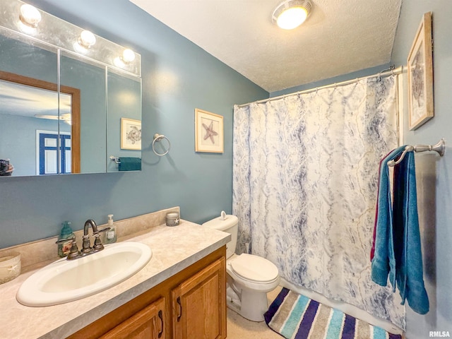 bathroom with a shower with curtain, vanity, a textured ceiling, and toilet