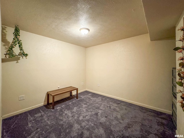 spare room with dark carpet and a textured ceiling