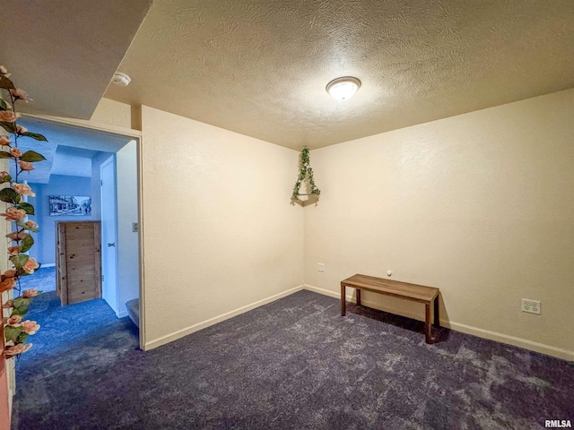 spare room with dark carpet and a textured ceiling