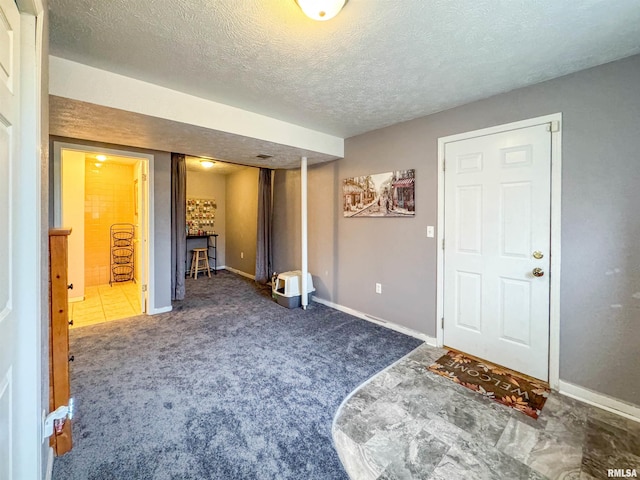 entrance foyer with dark colored carpet and a textured ceiling