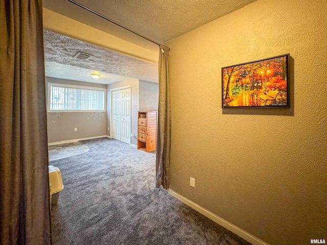 hallway featuring a textured ceiling and carpet floors