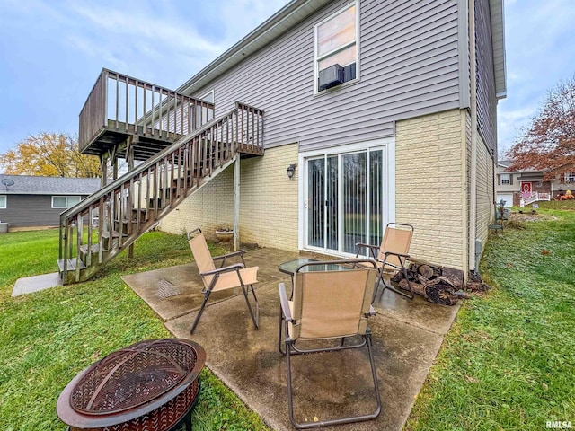 back of house featuring a patio, a fire pit, a deck, and a lawn