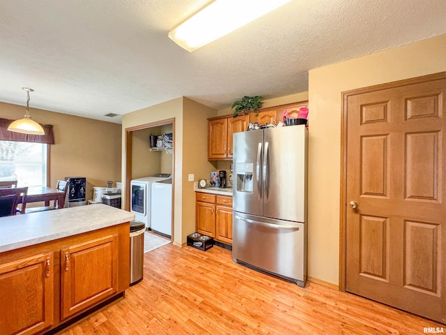 kitchen featuring stainless steel fridge, a textured ceiling, pendant lighting, light hardwood / wood-style flooring, and washing machine and clothes dryer