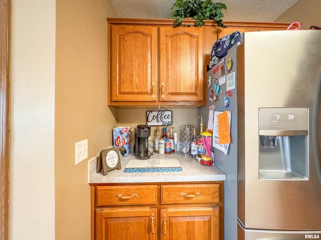 kitchen with stainless steel fridge and a textured ceiling