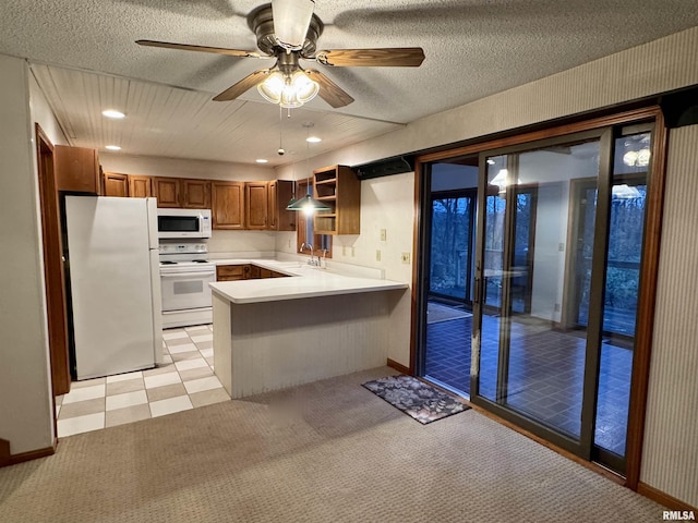 kitchen featuring a peninsula, white appliances, a sink, light countertops, and brown cabinets