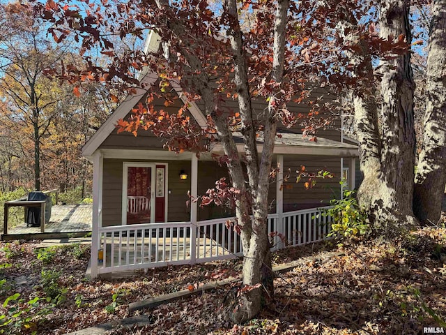 view of property hidden behind natural elements featuring covered porch