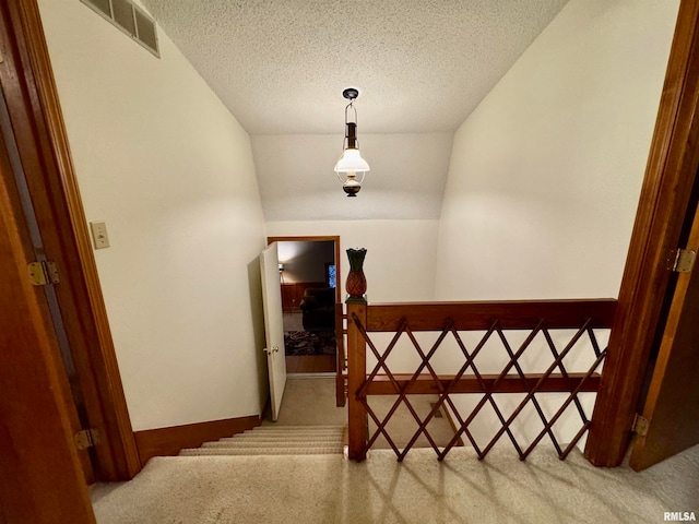 staircase featuring a textured ceiling, carpet floors, visible vents, and baseboards