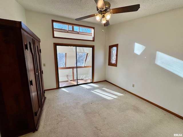 unfurnished room with a ceiling fan, light colored carpet, a textured ceiling, and baseboards